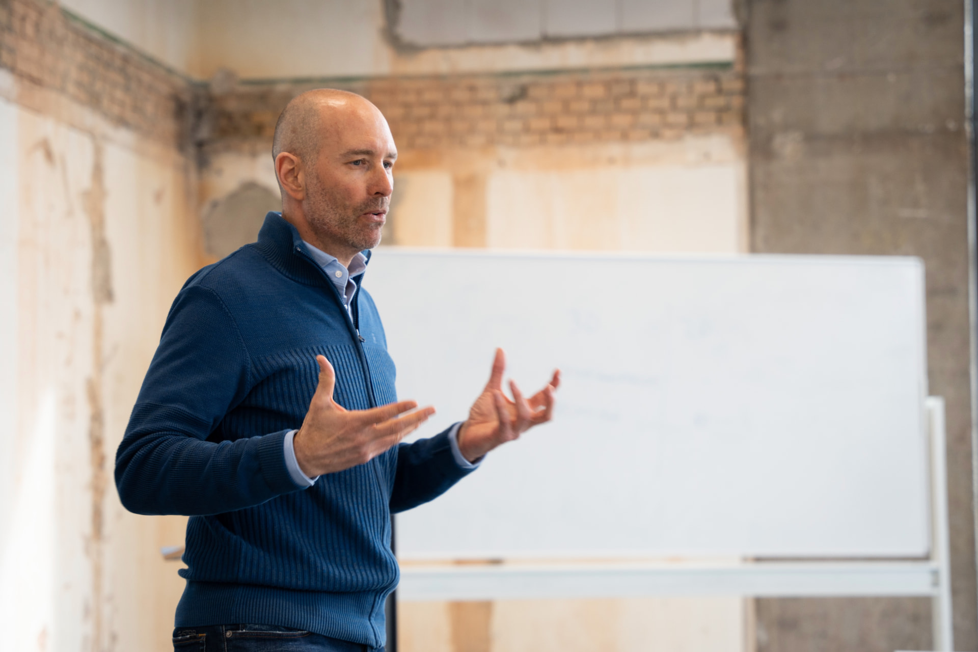 Ashley Usiskin in a blue jumper facilitating a session in front of a whiteboard